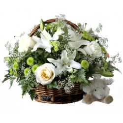Composition dans un panier avec des lys et des roses blanches.